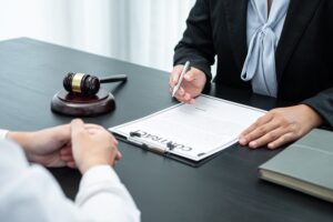 A male lawyer or counselor discussing a legal case negotiation with a client in an office, reviewing contract documents, with elements of law and justice symbolizing the lawsuit concept.






