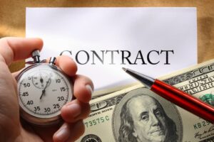 Concept of a contract involving money, a pen, and a hand holding a stopwatch.






